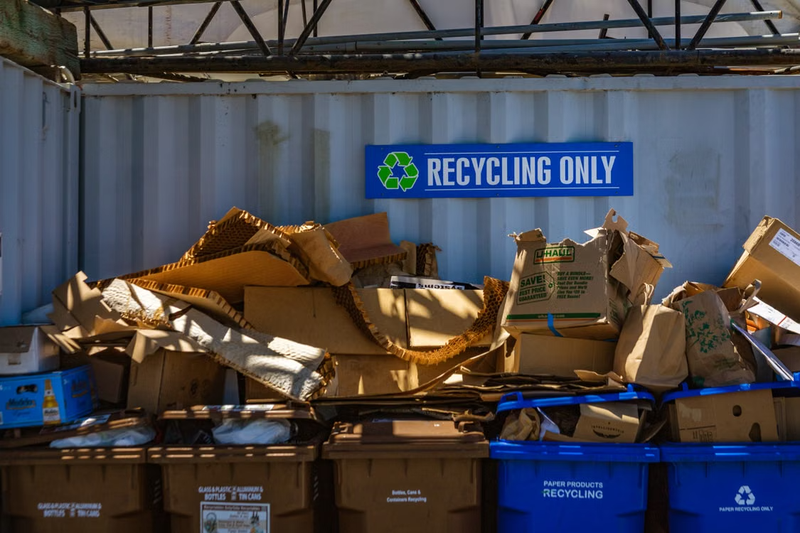 Sorted cardboard and recyclables in bins under a Recycling Only sign